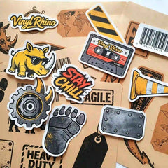 A diverse collection of Vinyl Rhino custom sticker samples featuring high-quality die-cut designs, industrial textures, and a holographic vinyl background.